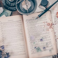 洋書が置かれた魔女の机とドライフラワー、水晶の写真