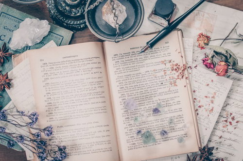 洋書が置かれた魔女の机とドライフラワー、水晶