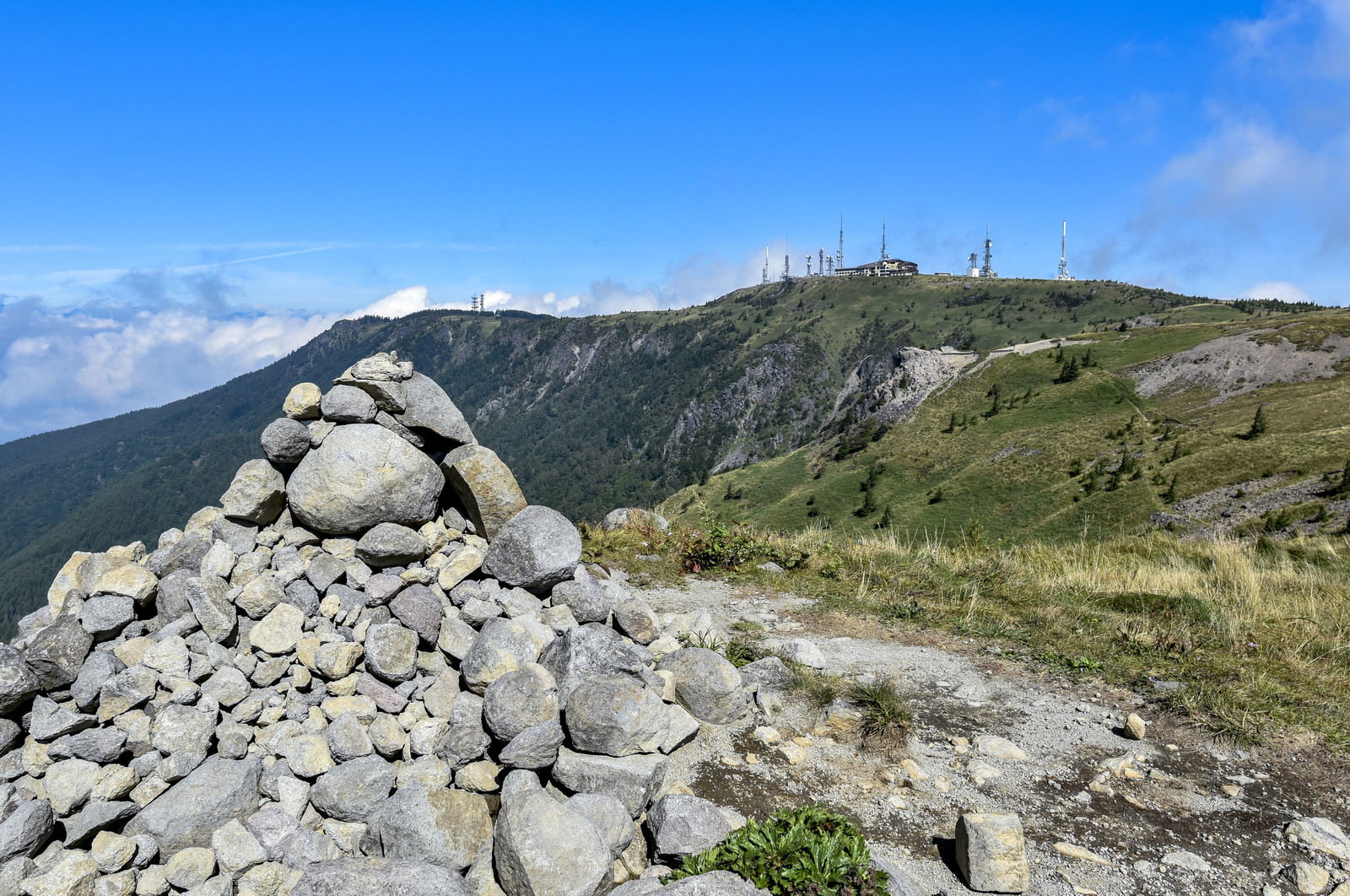 美ヶ原高原の登山道に積まれた石のケルンと青空、遠方の山並み
