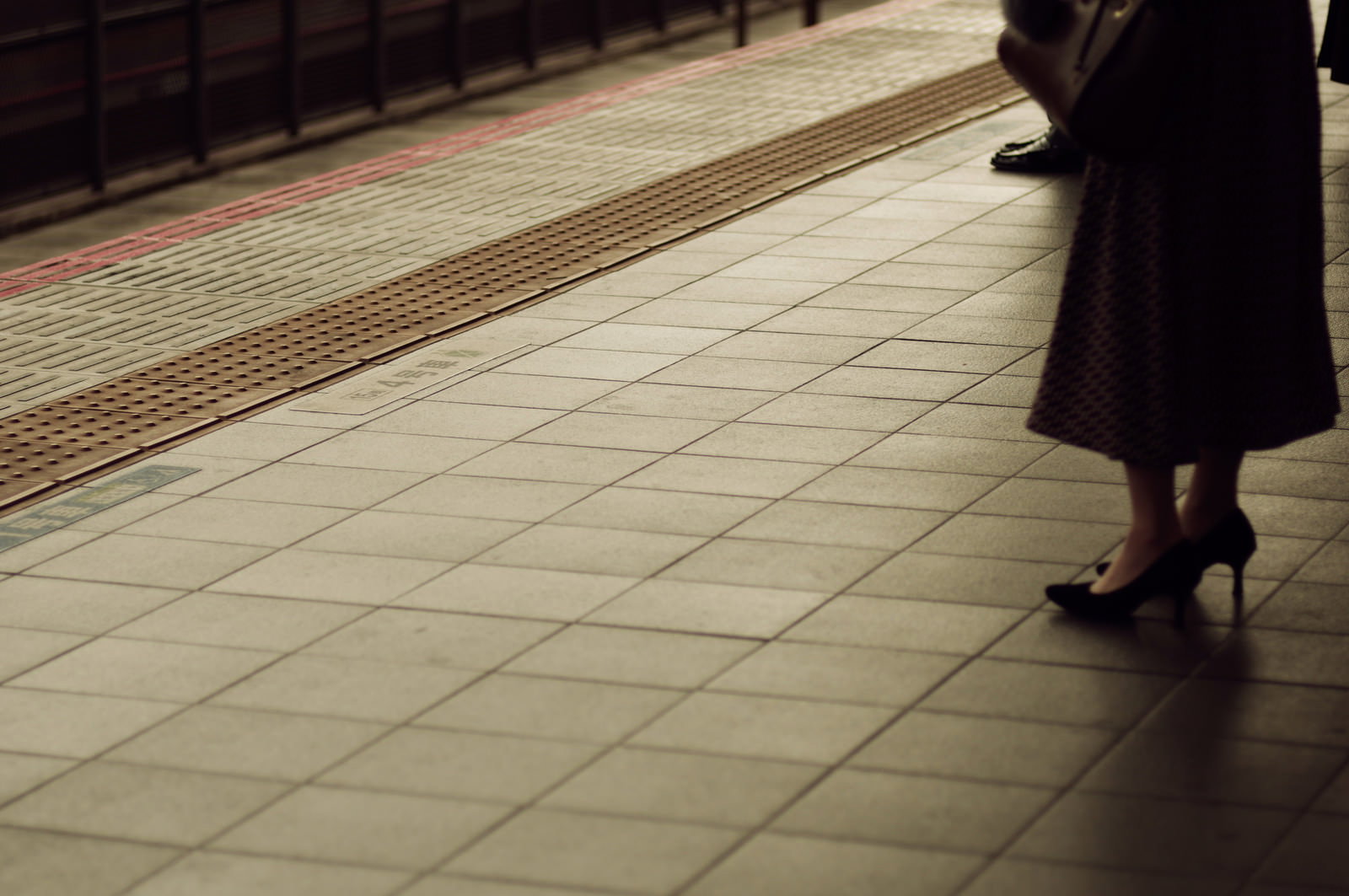 点字ブロックが敷かれた駅のホームで通勤する人の足元