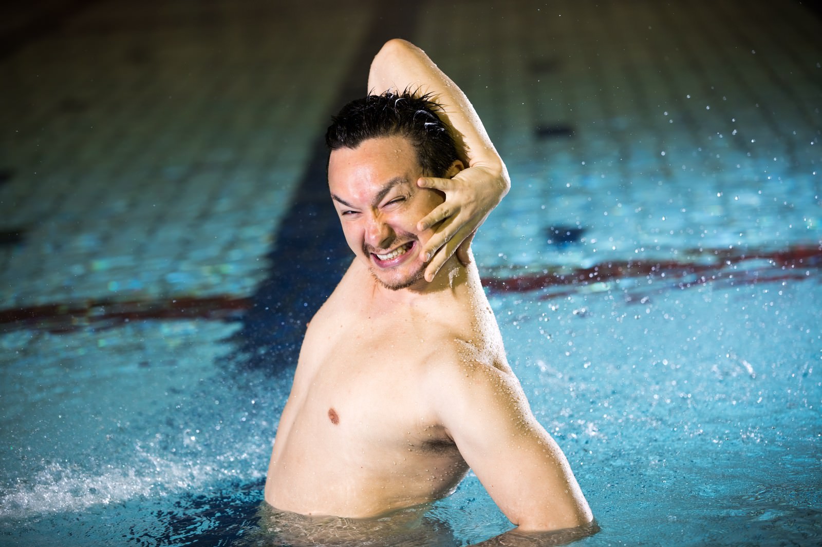 プールの中で片手を頭に当てて苛立った表情を見せる男性［モデル：Max_Ezaki］