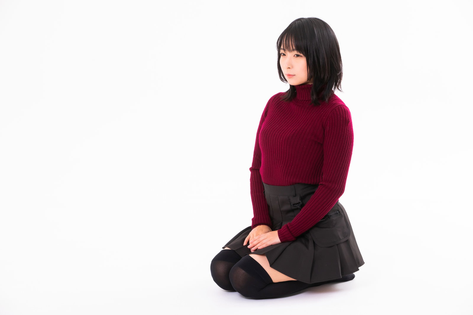 えんじ色のセーターで正座する黒髪の女性［モデル：にゃるる］