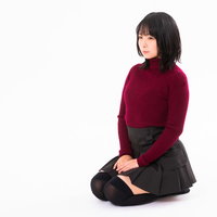 えんじ色のセーターを着て正座する女性のポートレートの写真