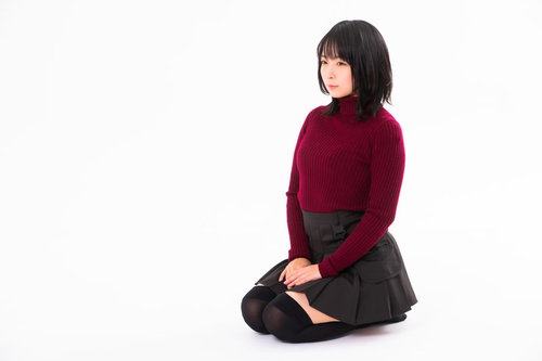 えんじ色のセーターを着て正座する女性のポートレート