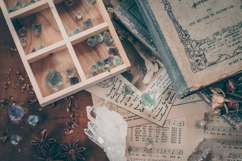 古い洋書と水晶が散らばる魔女の机のアンティークな配置