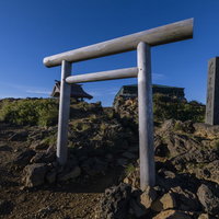 蔵王山の山頂に立つ白い鳥居と石碑、宮城県の雄大な山岳風景の写真