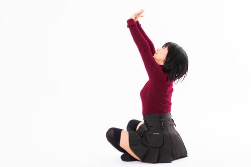 胡坐をかいて両手を上に伸びをする女性のストレッチポーズ
