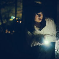 暗闇の中、懐中電灯を照らして肝試しする女性の写真