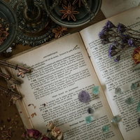 魔女の机に並ぶアンティークな洋書とドライフラワー、天然石の結晶の写真