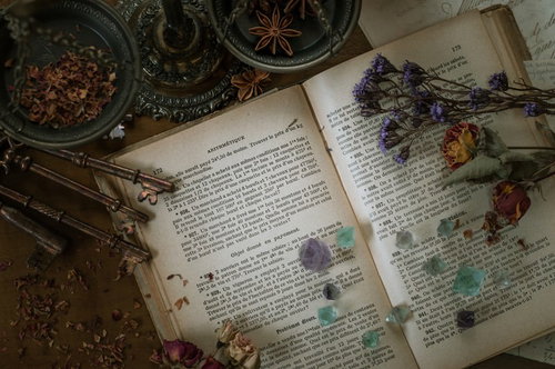 魔女の机に並ぶアンティークな洋書とドライフラワー、天然石の結晶