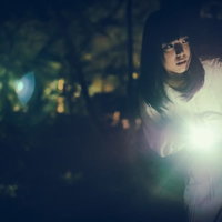暗闇で懐中電灯を持ちながら周囲を警戒する女性の写真