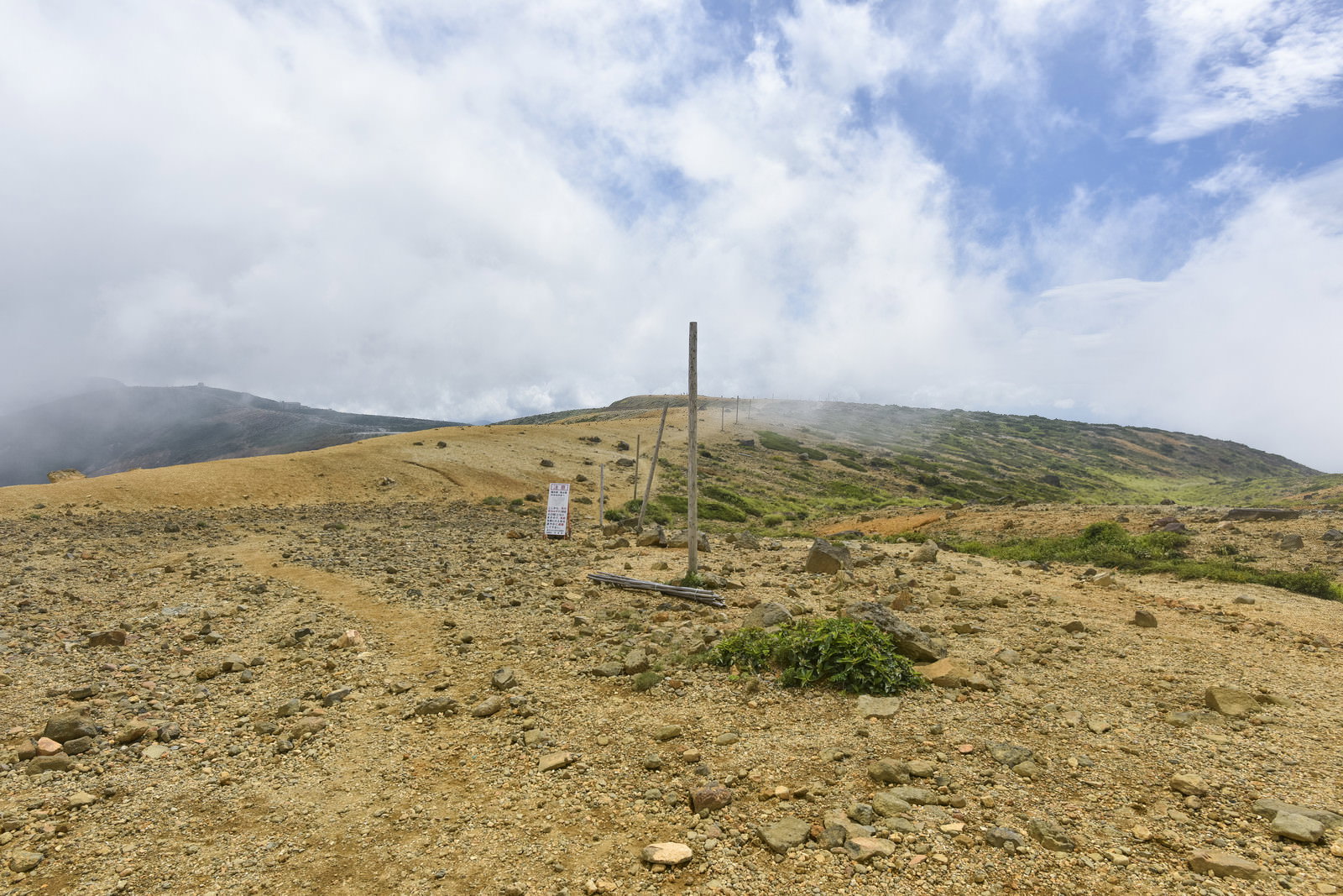 蔵王山の稜線に等間隔で立つ登山道ポールと雲の流れる空