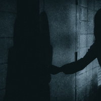 暗闇の扉をあける人影の写真