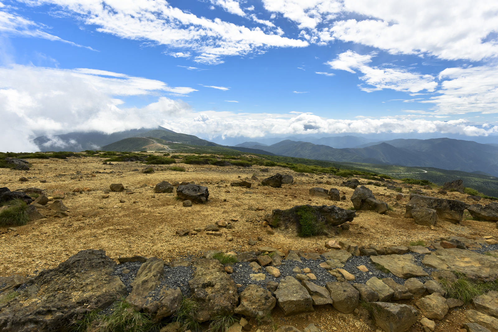 青空の下、ゴツゴツした岩石が散らばる蔵王山の山頂付近の荒涼とした風景