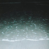 夜間の波打ち際に打ち寄せる波と砂浜の風景の写真