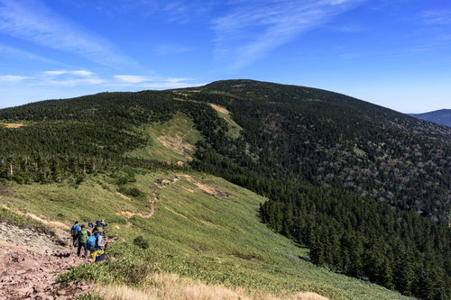 青空の下、緑の森林に覆われた西吾妻山への稜線
