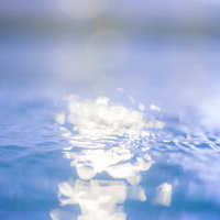 プールの水面に光が反射する波と波紋の様子の写真