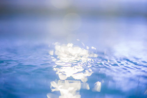 プールの水面に光が反射する波と波紋の様子