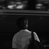 踏切待ちする学生と走る電車の写真