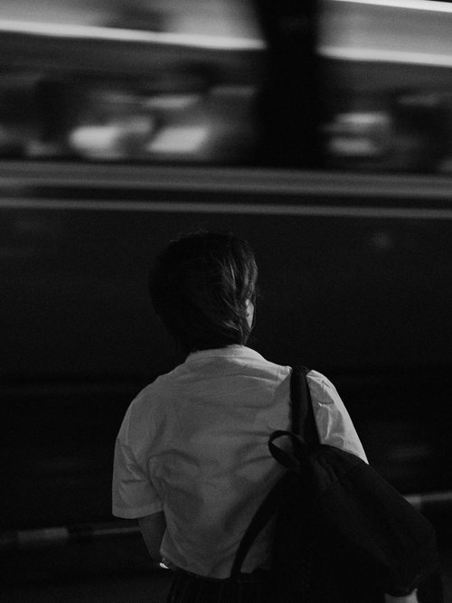 踏切待ちする学生と走る電車