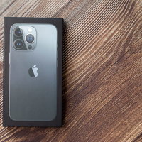 iPhone 13の箱を木目テーブルに置いた開封の儀の写真