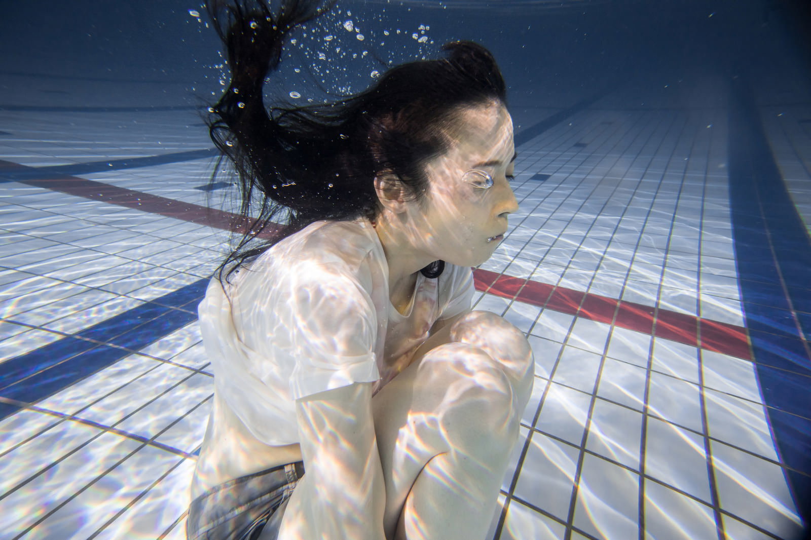プールの水中で息を止めて目を閉じている女性［モデル：たけべともこ］