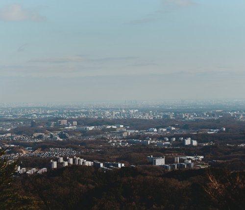 山上から見た広がる街並みと曇り空、遠景の都市部