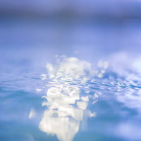 屋内プールの青い水面に映る光の反射と波紋の写真