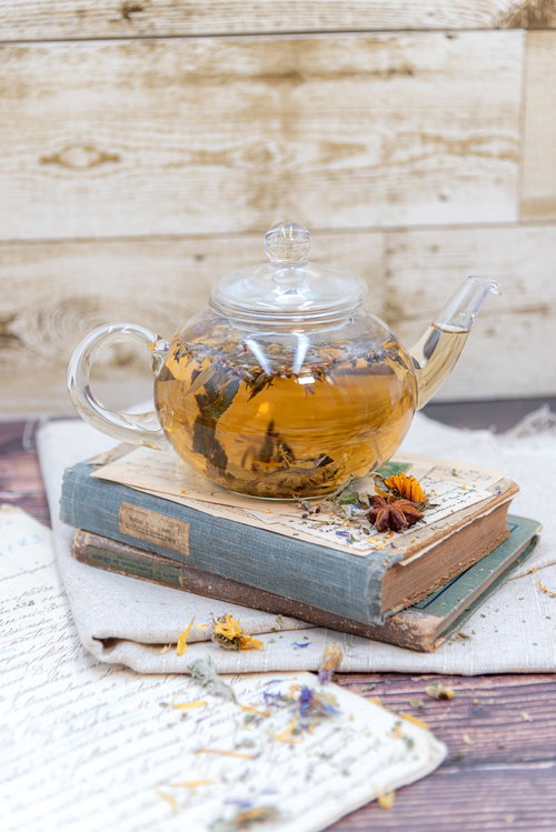 洋書の上に置かれたハーブティーとティーポット