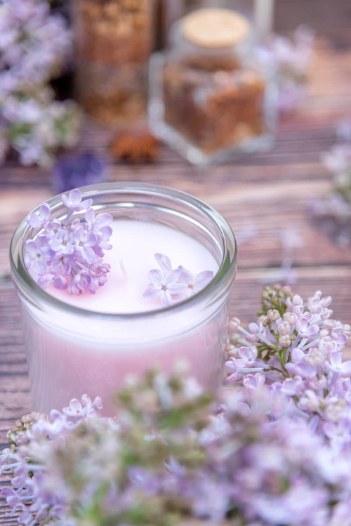 白いキャンドルに飾られたライラックの花のアレンジメント