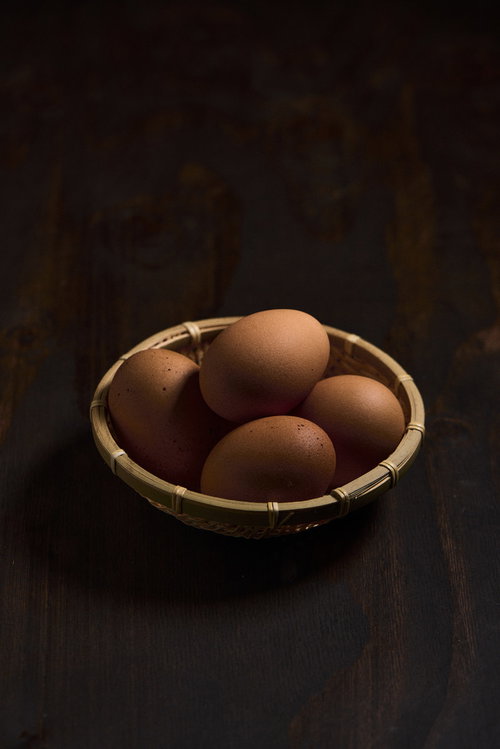 卓上の竹かごに入った生卵と新鮮な食材