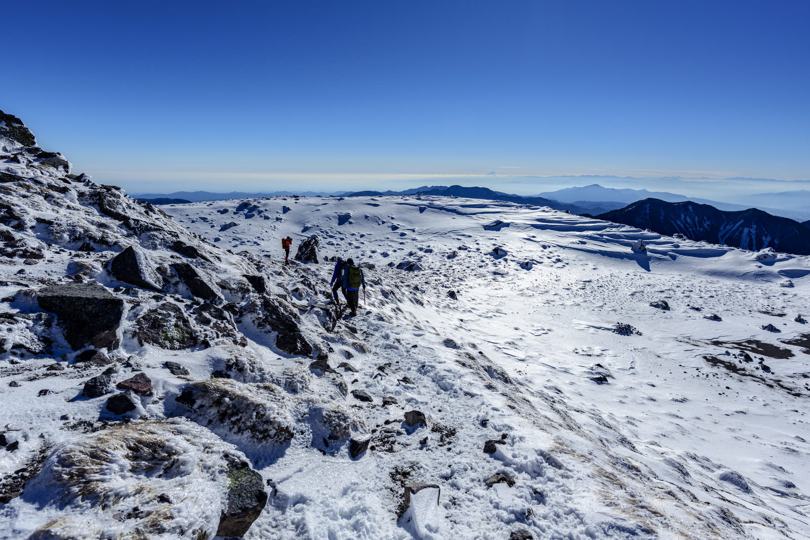 雪と氷で覆われた日光白根山の山頂で登山者が歩く様子