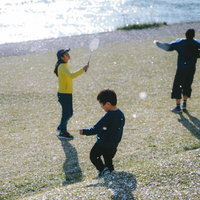 河川敷で桜吹雪を追いかけるこどもたち、春の季節を楽しむ子どもたちの写真