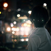眠らない街の夜景に照らされた帰宅中の高校生の後ろ姿の写真