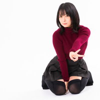 膝をついてVサインする赤紫のニット姿の女性の写真