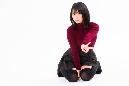 膝をついてVサインする赤紫のニット姿の女性