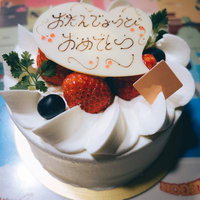 おたんじょうびおめでとうと書かれたクリームケーキの写真