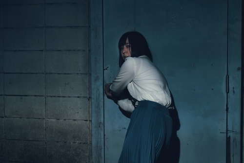 何かに追われて廃屋に逃げ込もうとする女性