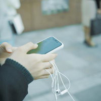 有線イヤホンを持ちながらスマホを操作する女子高生の手元の写真