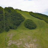 恩原高原スキー場の初夏、緑に覆われた草原と周囲の山々の写真
