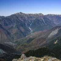 青空の下、中腹が紅葉に染まる笠ヶ岳の秋景色の写真