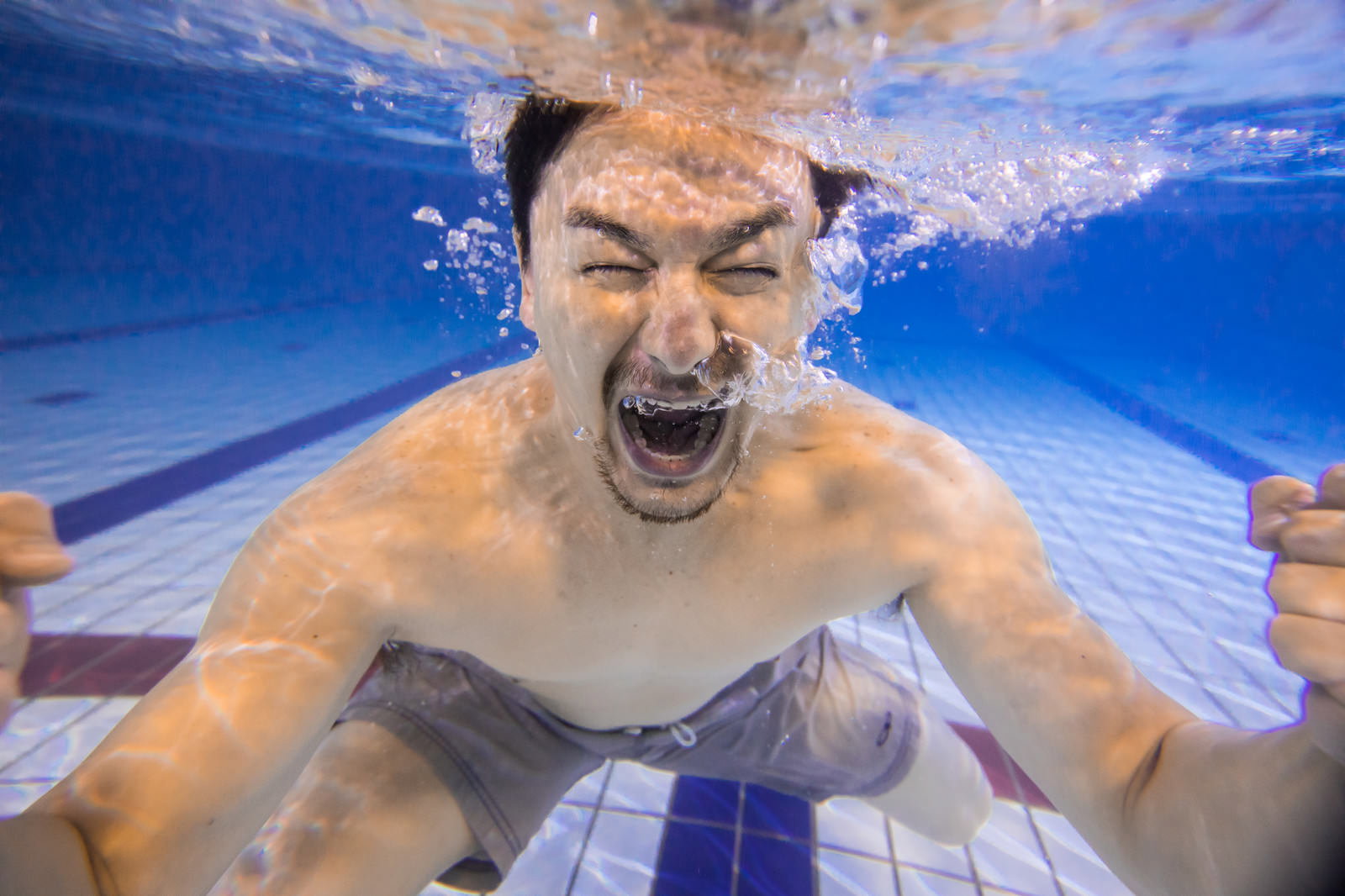 プールの水中で大きく笑顔を見せる男性