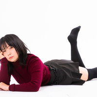 赤い長袖で頬杖をついて横たわるポージング中の女性の写真