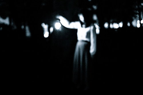 ランタンを持って暗闇を徘徊する女性の不気味なシルエット