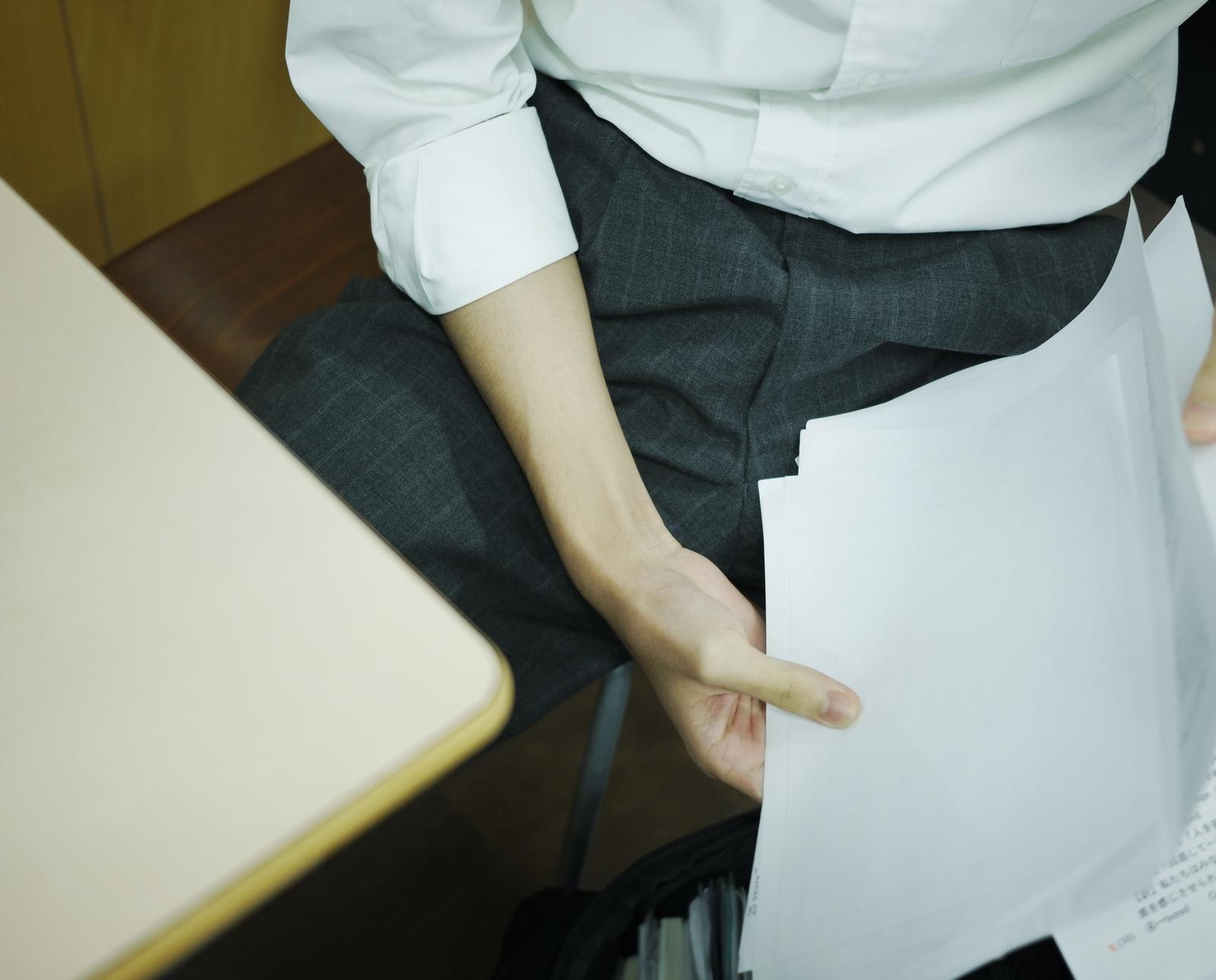 プリントを整理してファイルにはめ込む学生の手元