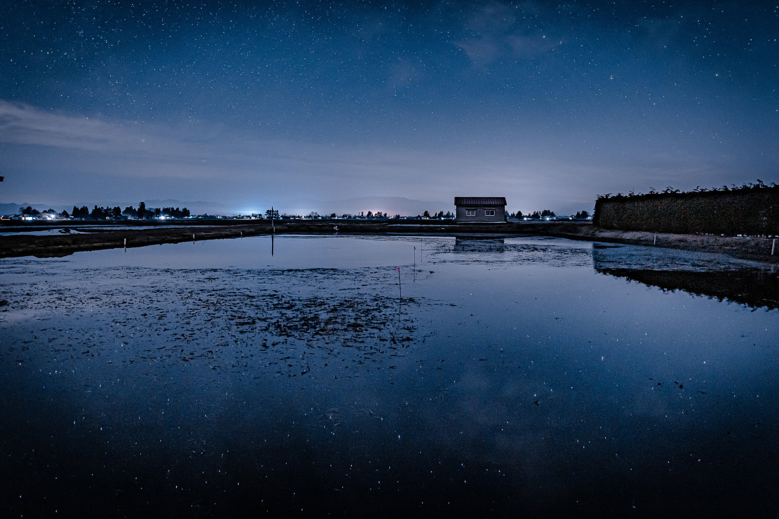 水を張った田んぼに星空が映り込む夜の田園風景