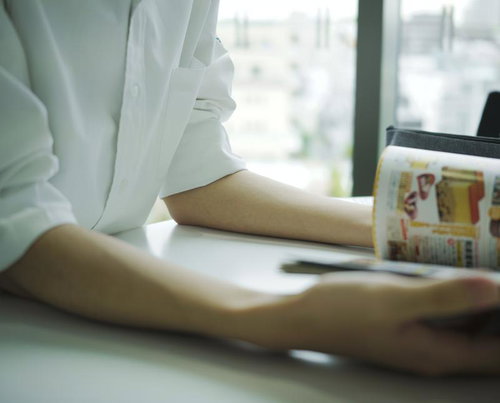 教室の机で雑誌を広げて読む高校生