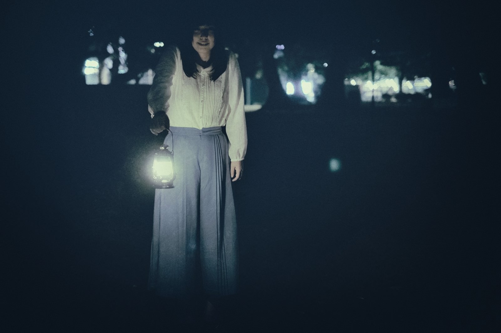 暗闇の中でランタンを手に持つ白い服を着た謎の女性［モデル：さとうゆい］
