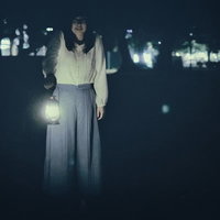 暗闇の中でランタンを手にした謎の女性、白い服で夜間に立つ不気味な姿の写真