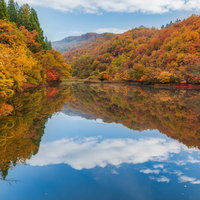 紅葉した山々が映る湖面の秋の空の写真